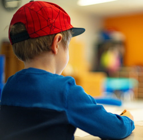 a-young-boy-sitting-at-a-table-writing-on-a-piece-of-paper.jpg a young boy sitting at a table writing on a piece of paper